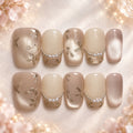 Short square nude and champagne press-on nails with pearl accents and metallic botanical details