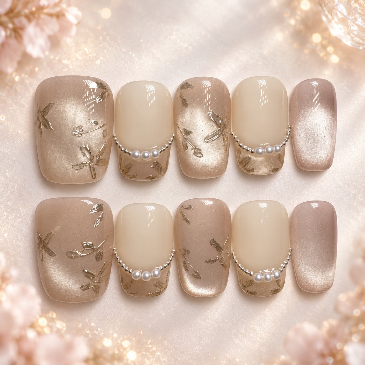 Short square nude and champagne press-on nails with pearl accents and metallic botanical details