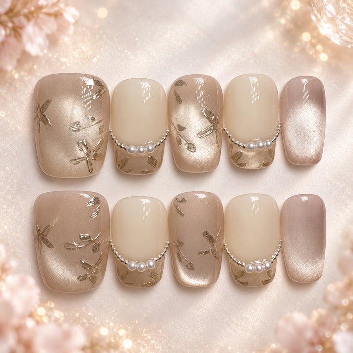 Short square nude and champagne press-on nails with pearl accents and metallic botanical details