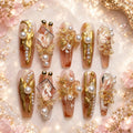 Long coffin nude press-on nails with gold, pearl, butterfly, floral and crystal embellishments