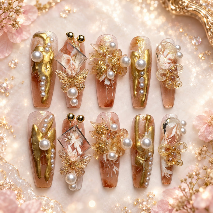 Long coffin nude press-on nails with gold, pearl, butterfly, floral and crystal embellishments