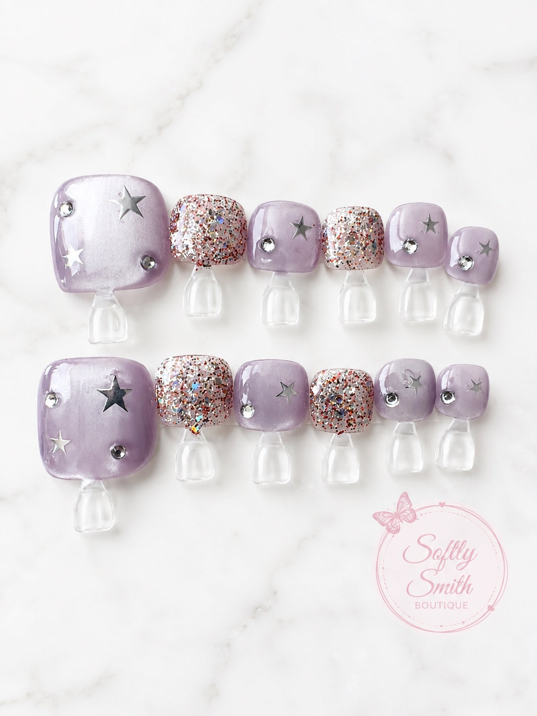 Sheer lavender press-on toe nails with silver stars, rhinestones, and glitter accents